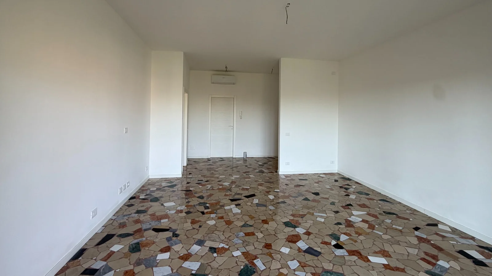 Soggiorno spazioso visto dalla zona finestrata verso l’ingresso